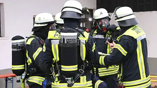 Eine Gruppe mit Feuerwehrleuten steht im Kreis