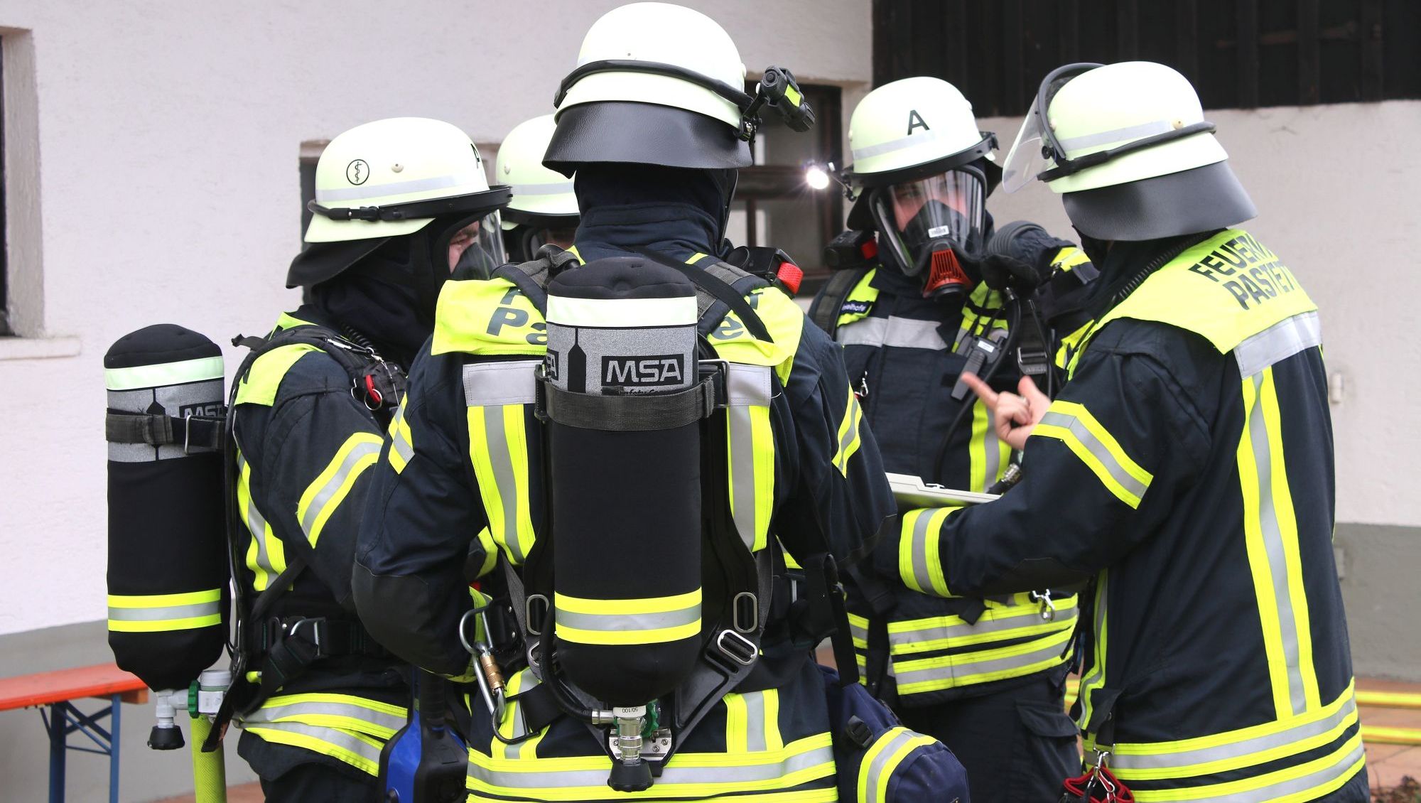 Eine Gruppe mit Feuerwehrleuten steht im Kreis