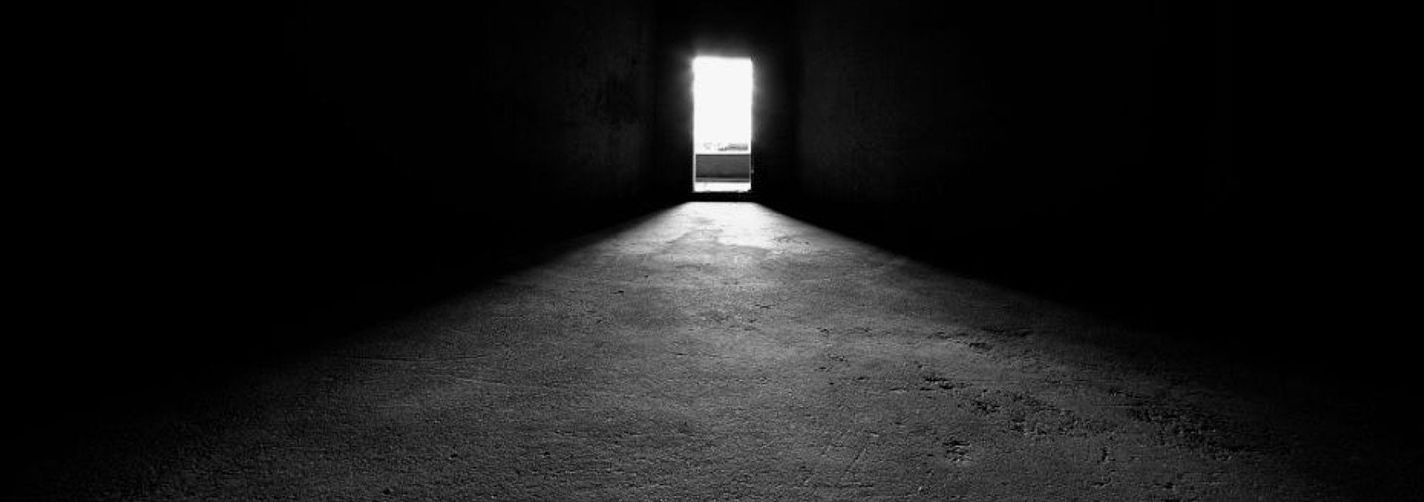 Eine geöffnete Tür lässt Licht in das Dunkle