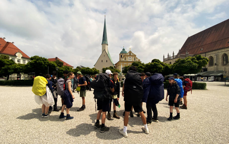 Pilger mit Rucksäcken stehen vor der Kirche in Altötting