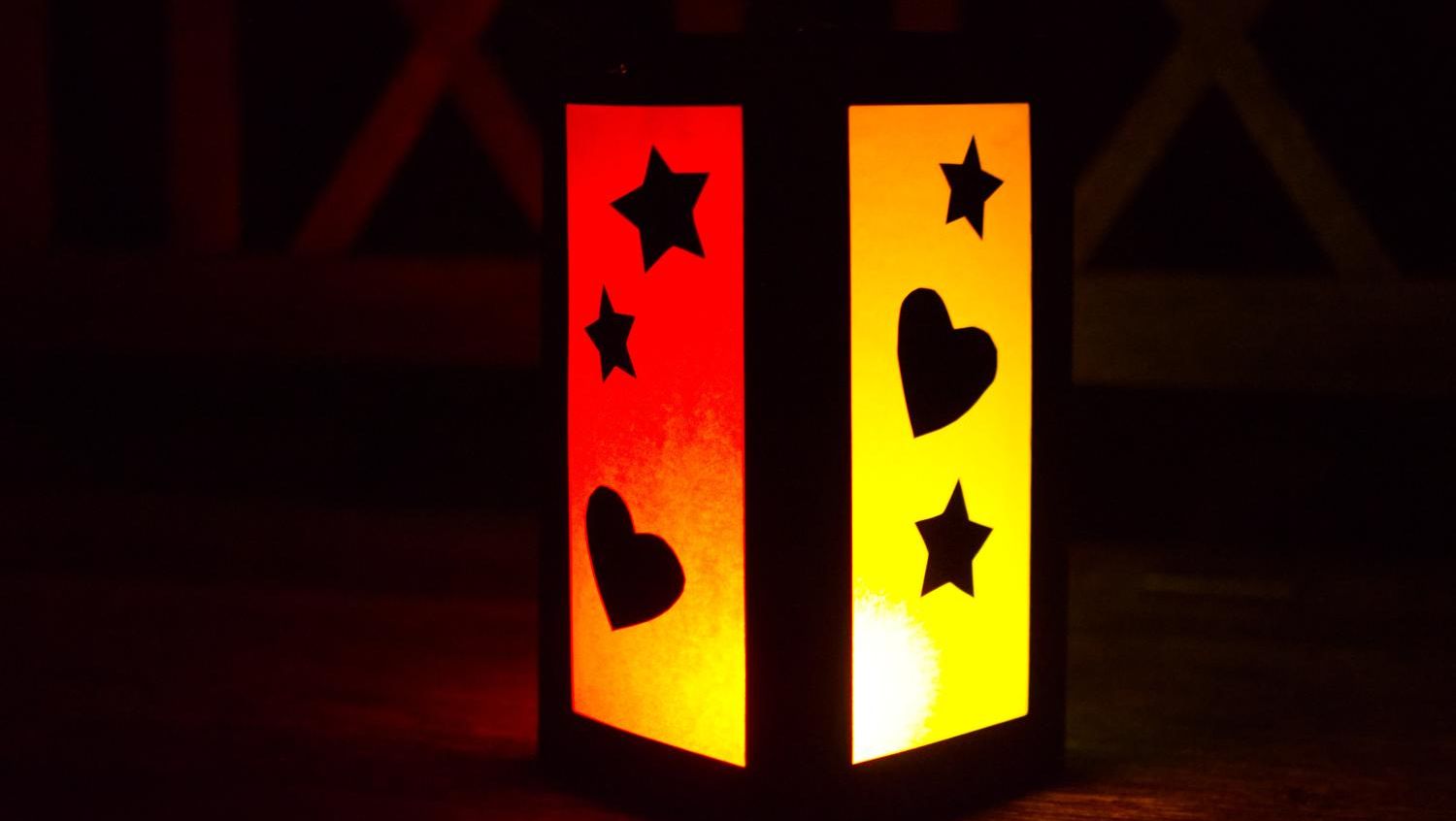 Eine gelb und rot leuchtende Papierlaterne mit Sternen-und Herzmuster.