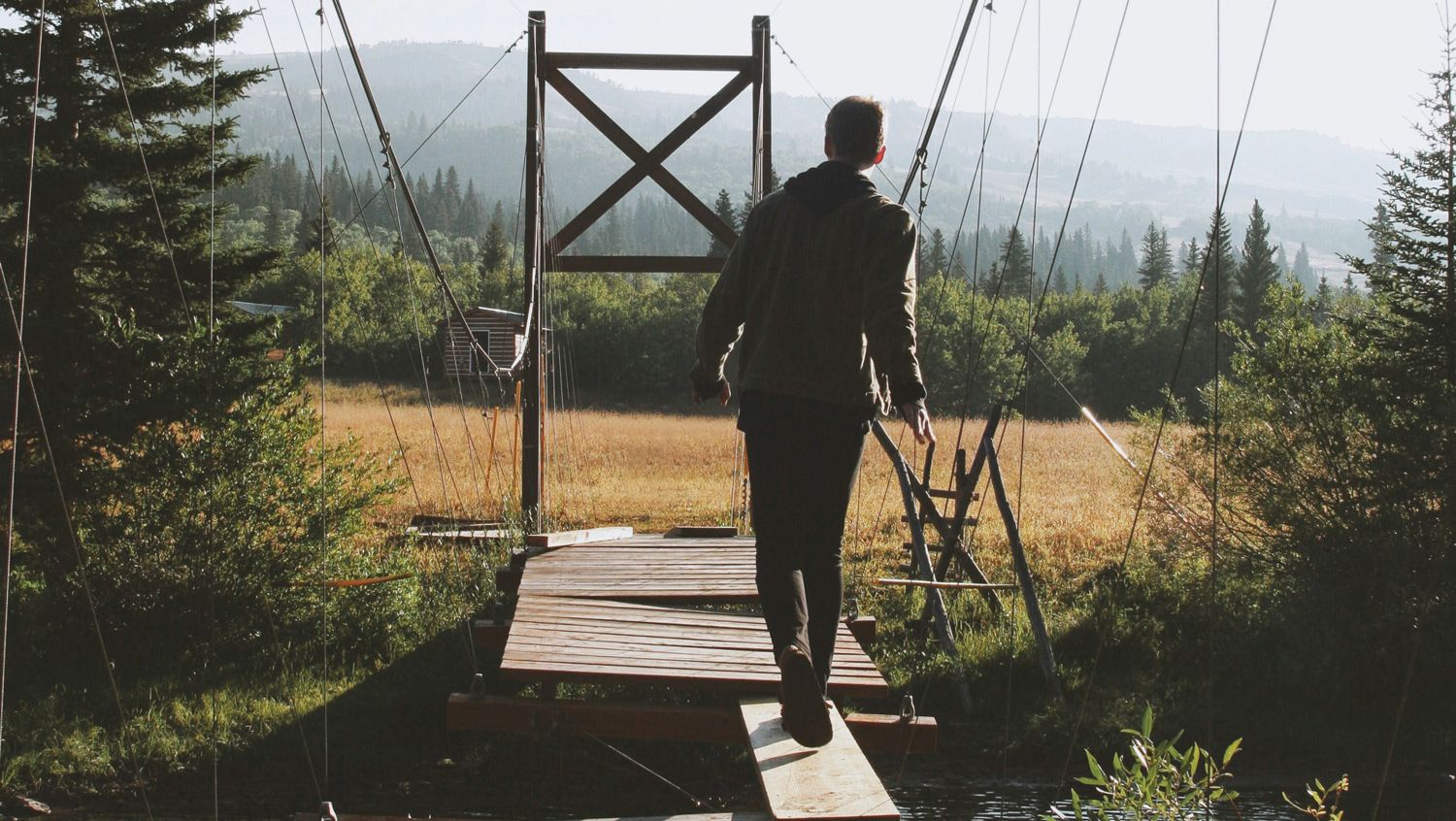Eine Person überquert eine kaputte Brücke mit Hilfe eines Brettes
